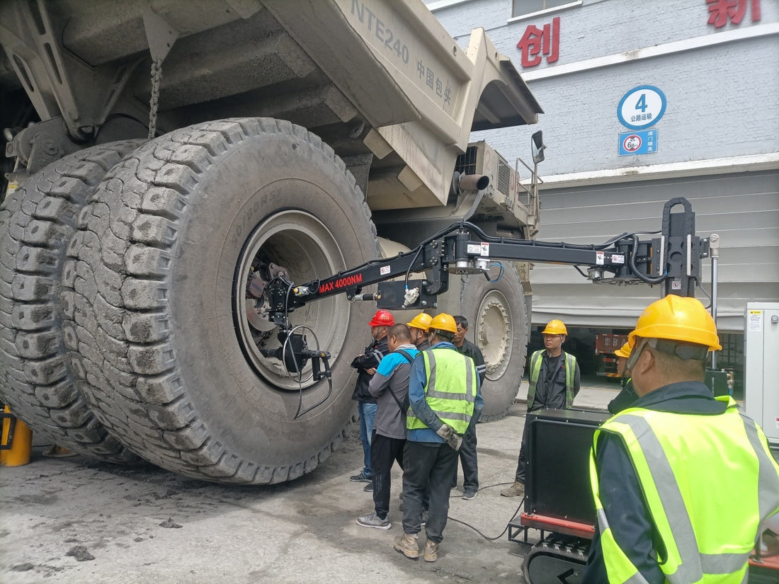 Mobile tracked 4000Nm torque reaction arm tightening massive bolts on a mining truck wheel.